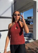 Top tejido color beige con lurex, de breteles finos y escote halter cruzado con abertura central.