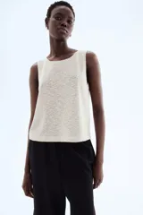 Musculosa color beige claro en punto texturizado con escote redondo y abertura de cerradura con botón en la nuca. Sin mangas.