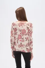 Sweater de tejido de punto, color crema, con estampado floral en tonos rosados y marrones. Presenta cuello redondo y mangas largas.