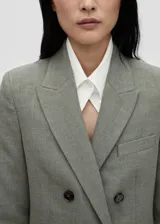 Blazer gris cruzado con cuello de pico con solapa, tejido de mezcla de lana, diseño recto y largo, manga larga con puños abotonados, forro interior y bolsillos de ribete en el pecho y de solapa laterales.