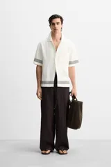 Pantalón relaxed fit color marrón oscuro confeccionado en tejido con mezcla de algodón y lino. Cintura elástica, bolsillos laterales y bolsillo trasero de plastrón. Perneras con pliegues frontales. Cierre en delantero con cremallera y botón.