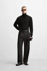 Pantalón negro de corte recto con cinturón de cuero sintético, pliegues frontales, bolsillos laterales y traseros con solapa.