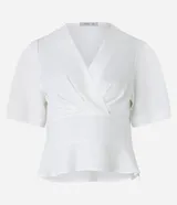 Blusa blanca de crepé con escote en V sobrepuesto, mangas cortas y recorte en la cintura con aspecto de volado.
