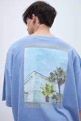 Remera celeste de algodón con calce boxy, teñida en prenda y con estampa fotográfica en la espalda.