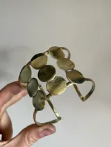 Brazalete hecho a mano en bronce, con diseño de formas circulares que se puede usar en el brazo o antebrazo.
