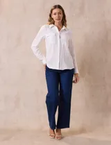 Camisa blanca de manga larga con cuello con solapa y abertura central con botones. Tiene dos bolsillos delanteros aplicados.
