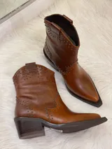 Botas cortas de cuero color marrón con punta fina, taco cuadrado y apliques de tachas metálicas.