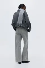 Pantalón de jean de tiro alto, color gris lavado, con pierna ancha y puños doblados. Presenta bolsillos de parche grandes en la parte delantera y bolsillos traseros.