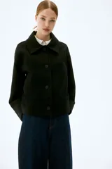 Campera corta negra de tejido de fieltro suave con cuello clásico y cierre frontal con botones. Modelo de corte holgado con hombros caídos y bolsillos insertados adelante.
