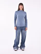 Polera rosa de tejido canalé, con cuello alto y mangas largas.