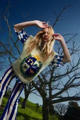 Chaleco de lana merino color crema, tejido y bordado a mano, con diseño de escudo con animales y sol.