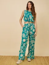 Pantalón largo verde con estampado de hojas y texto en color crema.