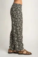 Pantalón recto con estampado de hojas color blanco sobre fondo negro, con cintura elástica y bolsillos laterales.