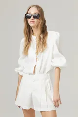Camisa blanca de lino con cuello mao, mangas largas abullonadas con puño elástico y corte holgado.