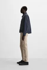 Pantalón chino azul marino, corte skinny fit, confeccionado en tejido de algodón con elasticidad. Cuenta con bolsillos frontales y traseros de vivo. Cierre frontal con cremallera y botón.