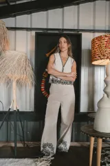 Pantalón de vestir color beige, de corte palazzo, con bordado de flores negras en el ruedo.