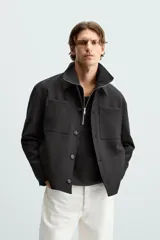 Sobrecamisa negra de corte cuadrado, con cuello solapa, manga larga con puños abotonados, bolsillos tipo parche en el pecho, bolsillos laterales y cierre frontal con botones.