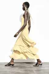Vestido midi amarillo pálido con tirantes finos ajustables y escote en pico. Falda con tres volantes en capas.