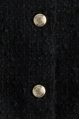 Chaqueta corta negra de bouclé con escote redondo y cierre frontal con botones dorados. Forrada.