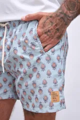 Short de baño celeste con estampado de flores rojas y hojas verdes.