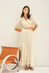 Falda larga de tiro alto, calce amplio, color crema con puntos dorados brillantes (lurex). La cintura es elástica en la parte trasera y tiene frunces.