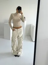 Pantalón cargo negro de denim rígido, corte wide leg, con bolsillos laterales y detalles de tiras con hebillas en los laterales.