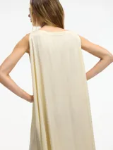Vestido largo color crema, de corte amplio y cuello redondo. Presenta tajos laterales verticales.