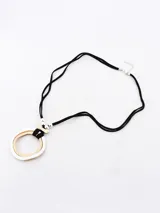 Collar con cordón negro y dije circular doble, uno plateado con textura martillada y otro dorado con textura de pequeñas esferas.