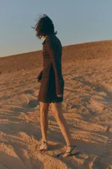 Vestido corto marrón de crochet con cuello camisero, botones dorados y mangas largas.