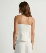 Blusa estilo corset color blanco, con escote recto, sin mangas, abotonado frontal y solapas aplicadas.