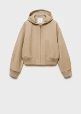 Chaqueta beige con capucha, cierre frontal con cremallera, puños y cintura elásticos.