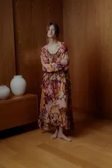 Maxi vestido con estampado floral en tonos naranja, rosa y borgoña. Tiene escote off-shoulder elastizado y mangas cortas con volados.