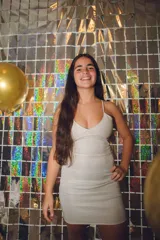 Vestido plateado con corte bajo el busto, abertura en la cintura y espalda descubierta. Se ata al cuello con dos tiras finas.