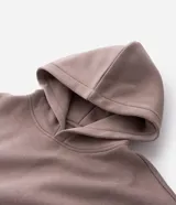 Buzo tipo canguro de color gris melange, con capucha, bolsillo canguro frontal y puños y bajo acanalados. Corte recto.