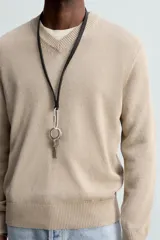 Jersey de punto color beige, con cuello en V y mangas largas.