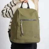 Mochila color verde oliva con bolsillo frontal con cierre y tirador de cordón. Tiene manija superior negra y tiras traseras acolchadas ajustables.