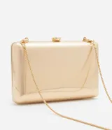 Cartera clutch rectangular rígida color dorado, con textura acanalada y cierre de broche. Incluye correa de cadena dorada desmontable.