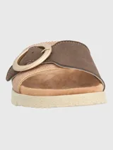 Sandalia marrón con tira ancha de tejido texturizado y hebilla circular decorativa.