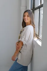 Remera beige de corte holgado con estampado de flores abstractas en dorado y negro.