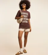 Remera marrón de algodón con cuello redondo y mangas cortas. Estampa frontal con la frase "Coffee First Existin Later" en letras blancas.