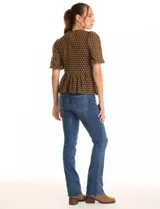 Blusa peplum marca Nanette, color negro con estampado de lunares dorados. Tiene escote a la base, mangas cortas con frunce y abertura con botón en la espalda. Incluye una musculosa interna a tono.