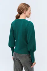 Sweater de tejido punto en color verde, con mangas largas abullonadas y detalles de botones en los puños.