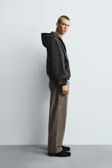 Cazadora negra de efecto piel con acabado lavado, corte boxy fit y capucha ajustable. Presenta cierre frontal de cremallera, bolsillos frontales tipo canguro y puños y bajo con elástico.