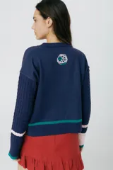 Buzo azul marino tejido en jacquard con diseño de frutas y verduras. Tiene mangas tejidas en ochos, bordado en la espalda y puños con agujerito para el dedo.