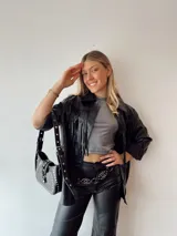Sobrecamisa oversize de ecocuero negro con flecos en la espalda y tachas plateadas.