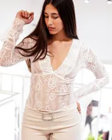 Blusa de encaje blanco con escote en V y mangas largas acampanadas.