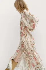 Vestido largo de viscosa con estampado floral, corte holgado, cuello redondo con botones y mangas globo largas. Incluye cinturón fino para atar.