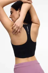 Top deportivo negro con escote en V, breteles finos cruzados en la espalda y copas removibles.
