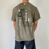Remera color verde oliva con efecto gastado, corte semi oversize y estampado en la espalda con dos tigres, flores y texto en japonés.