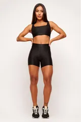Top deportivo negro con textura colmena 3D, escote cuadrado, breteles anchos y banda inferior con logo.